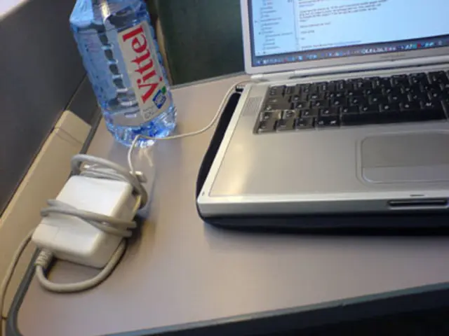 In this picture we can see a laptop and a socket, water bottle on a table.