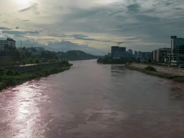 In this image there is a big river beside that there are so many buildings and plants.