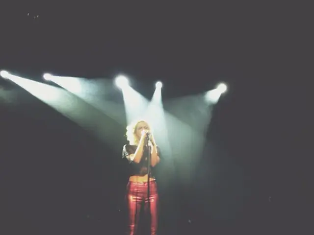A beautiful girl is standing and singing in the microphone. These are the lights.