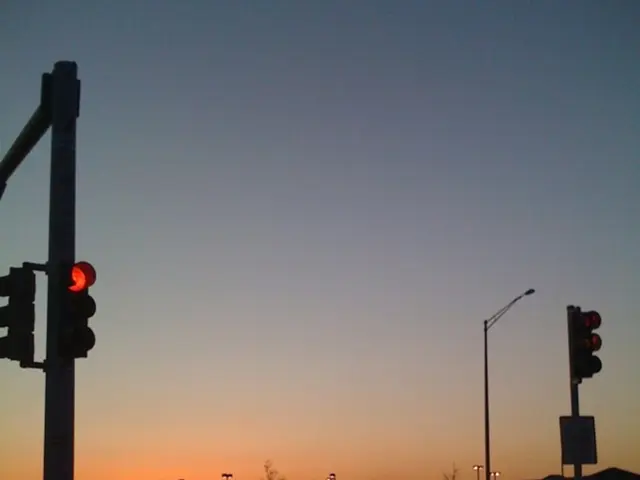 In this image I can see few traffic signals, background I can see few vehicles, few poles and the...