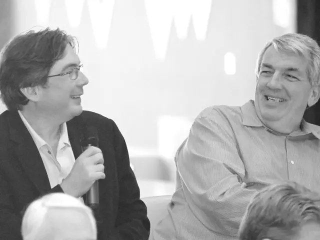 In this image we can see men who are sitting and one of them is holding a mic in his hands.