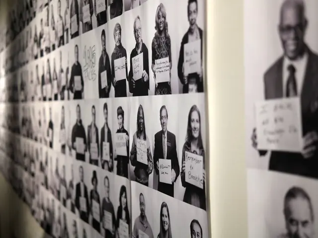 In this image I can see number of photos of people on the wall. I can see they all are holding...