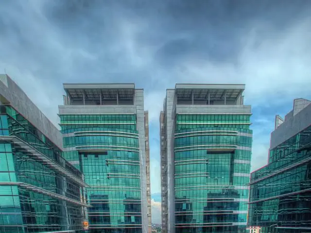 In this image I can see few buildings which are green in color, the ground, few trees, some grass...